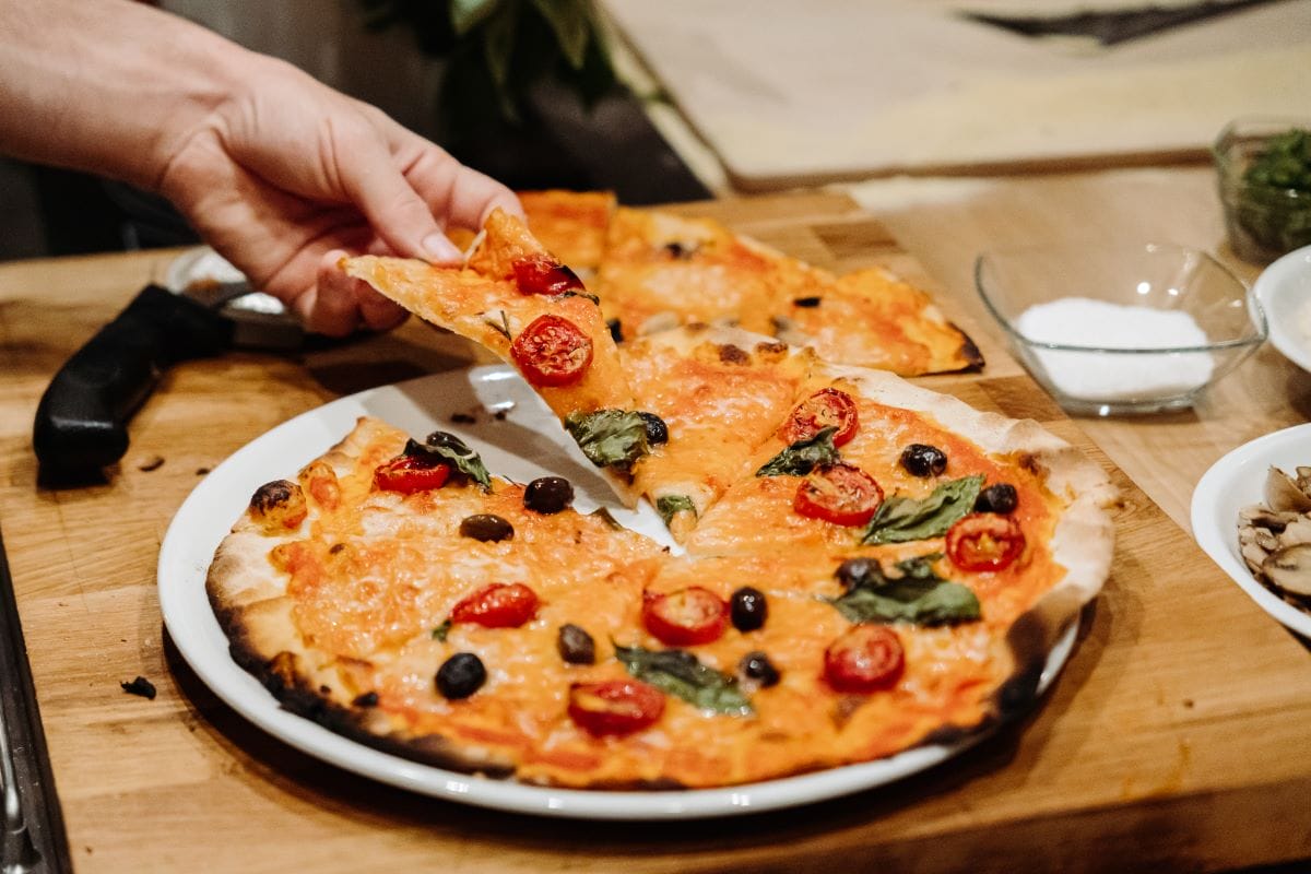 A person taking a slice from their pizza.