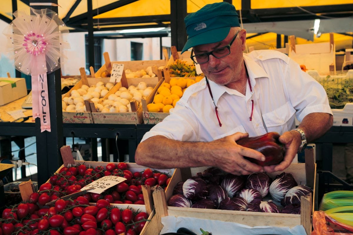 smiling man serving produce in market