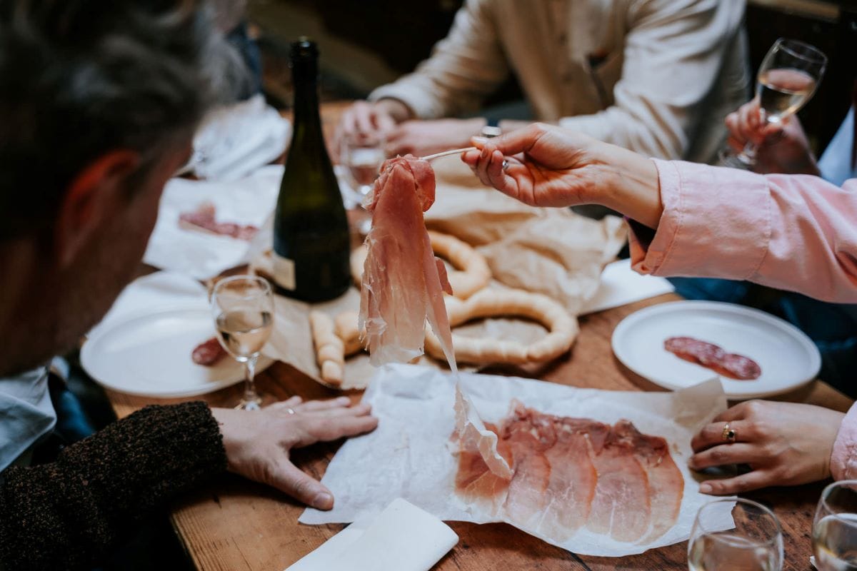 someone peeling a piece of ham off a plate with a fork