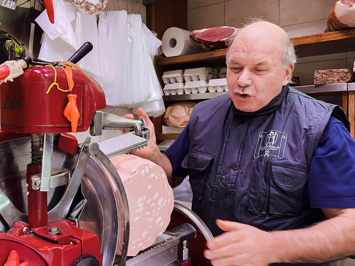 Man slicing mortadella through a machine