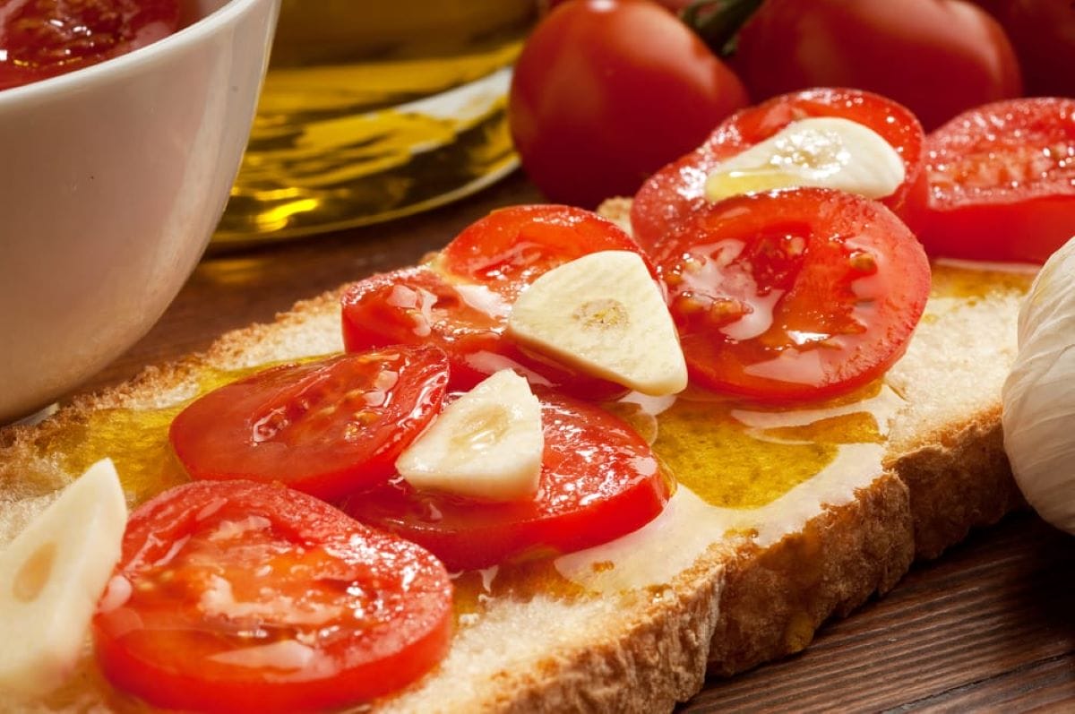 sliced loaf of bread with tomatoes and garlic pieces.