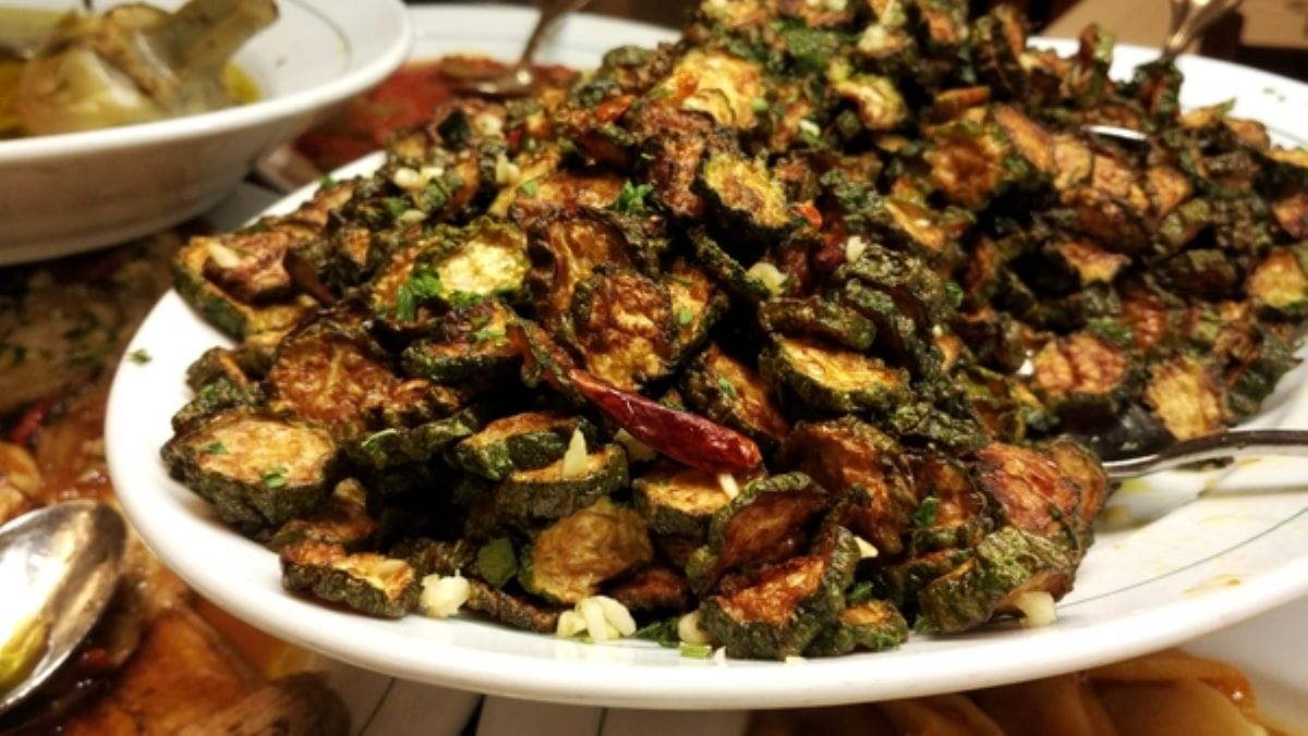 a large white plate topped with sauteed zucchini. 