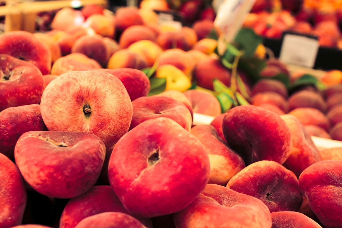 a bunch of ripe peaches at a market stall