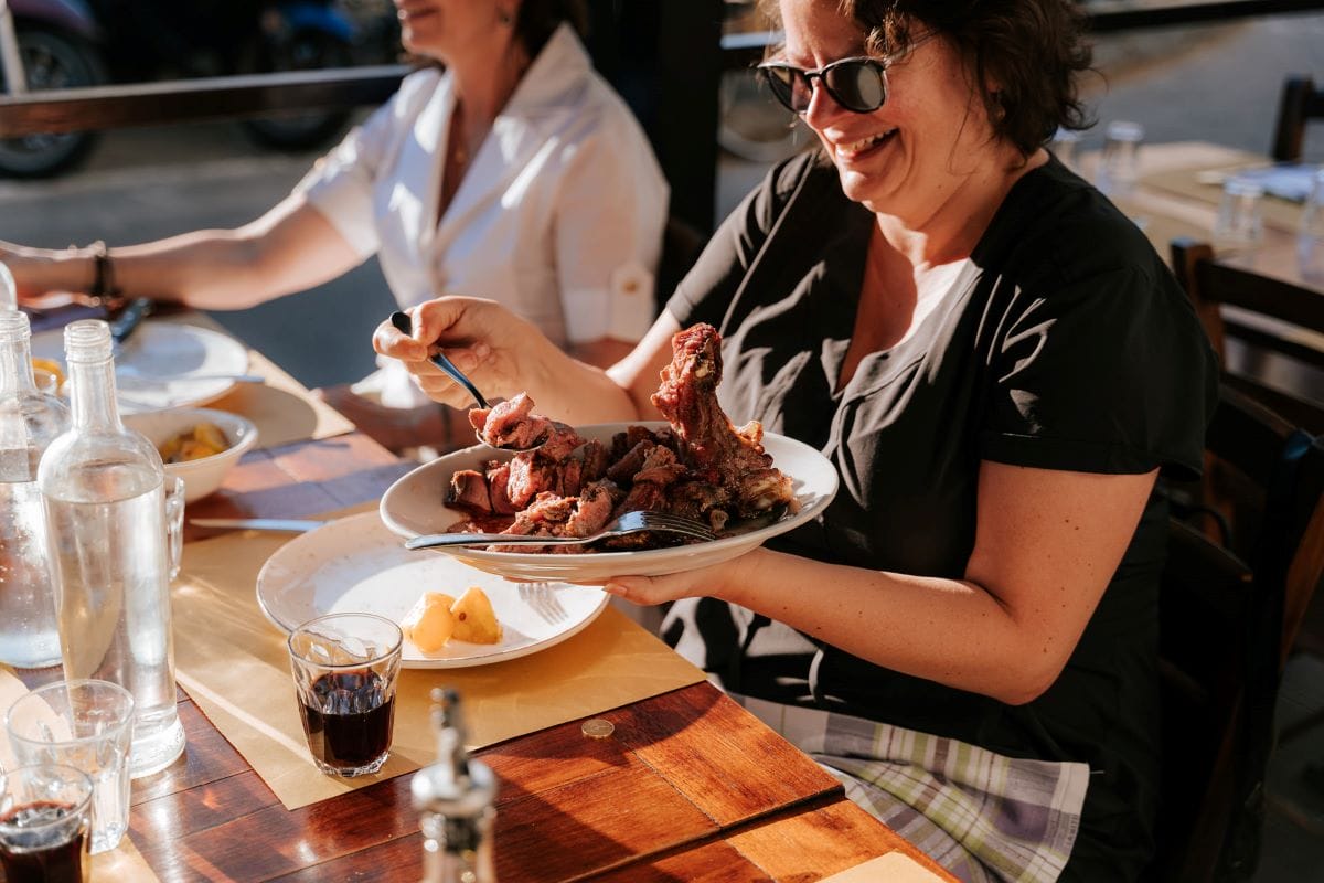 woman scooping meat or steak onto her plate.