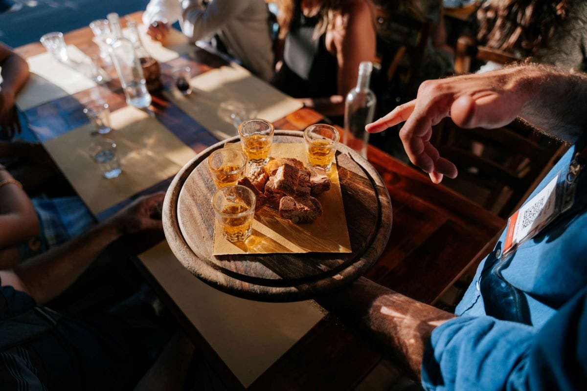 a round board with several small glasses and cookies