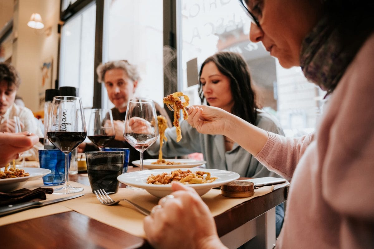 Guests on bologna food tour eating pasta and drinking wine at a restaurant