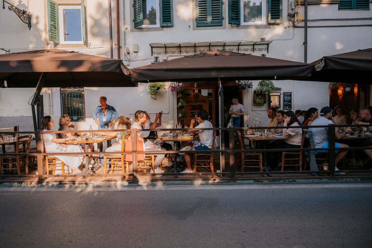 people sitting at tables under large umbrellas