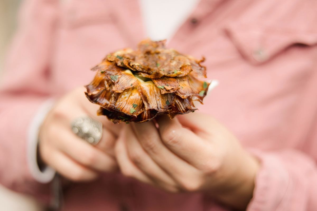 woman holding a fried artichoke