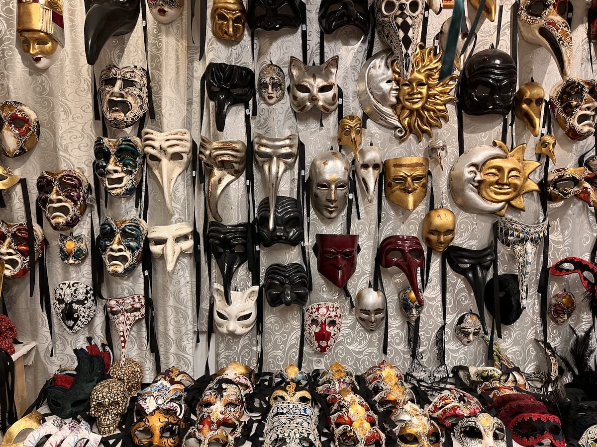 a wall of venetian masks of different colors and styles