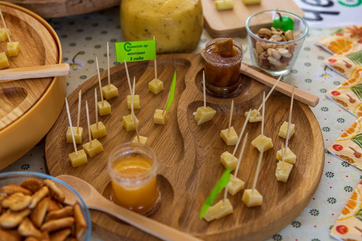 A wooden platter with cheese samples on it. 