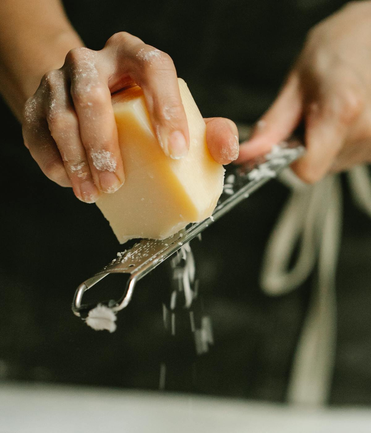 Parmigiano Reggiano being grated by a chef. 