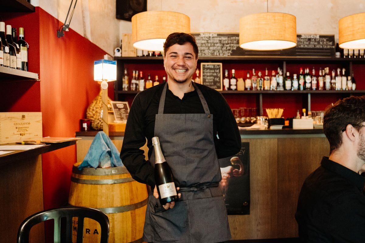 A waiter holding a bottle of prosecco at a restaurant in Rome, Italy.