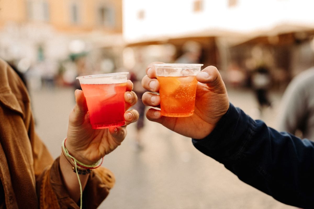 Close up of two people cheering spritz in Trastevere neighborhood.