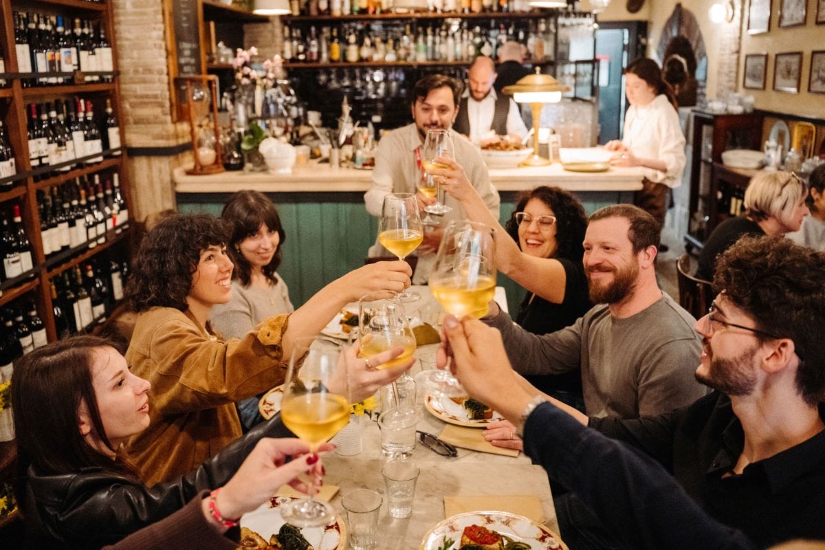 A group of people at a restaurant cheering wine glasses.