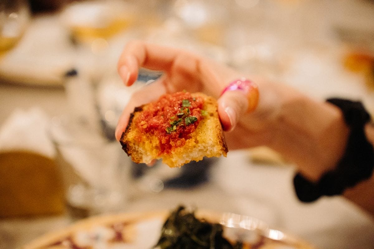 A person holding a eaten piece of bruschetta.