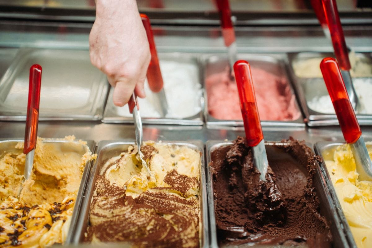 A display of gelato as a shop keeper takes a scoop.