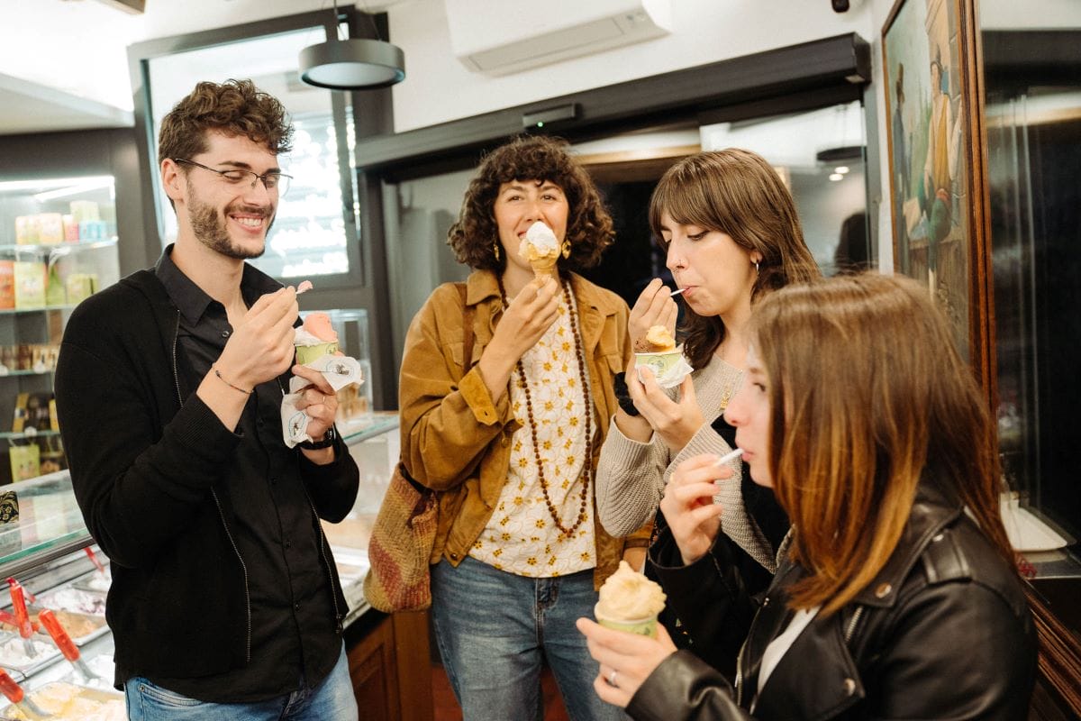 A group of people inside a gelato shop eating gelato.