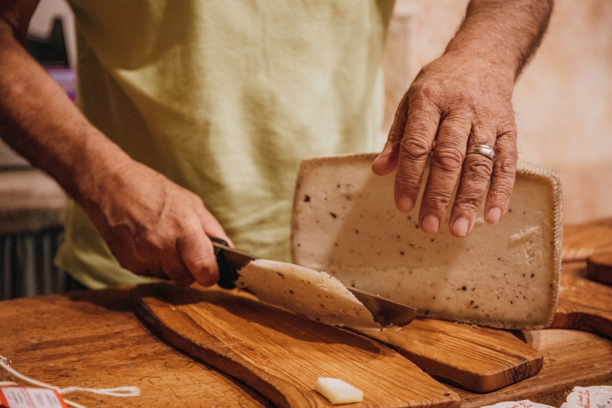 A man slicing thin slices of cheese.