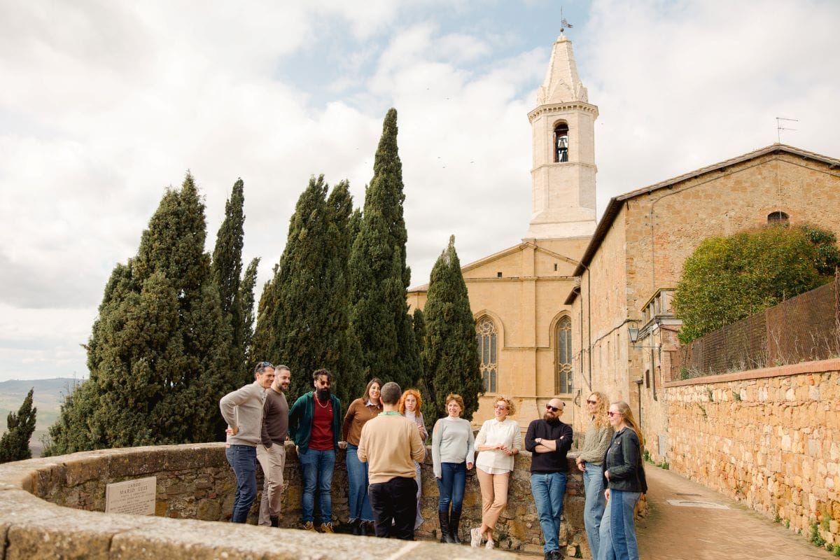 A group of people standing at a viewpoint in Pienza, taking in the view and listening to their tour guide.