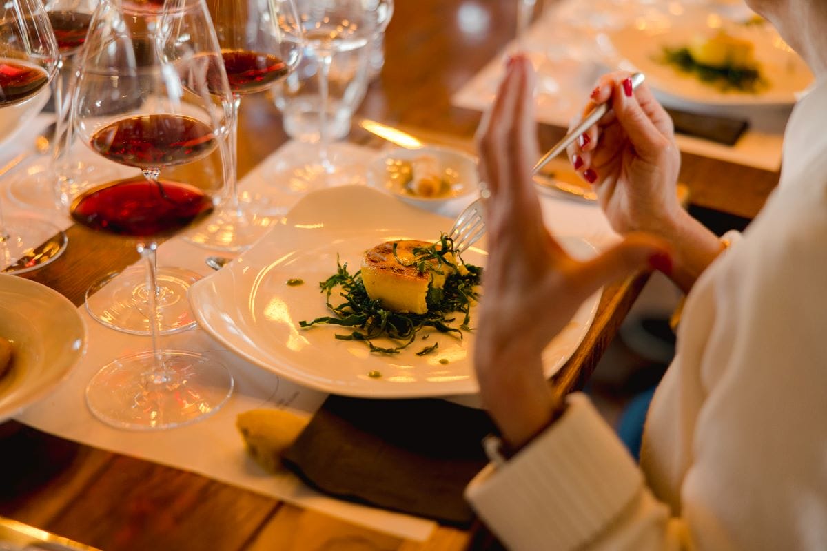 A woman eating typical Tuscan dishes and drinking wine.