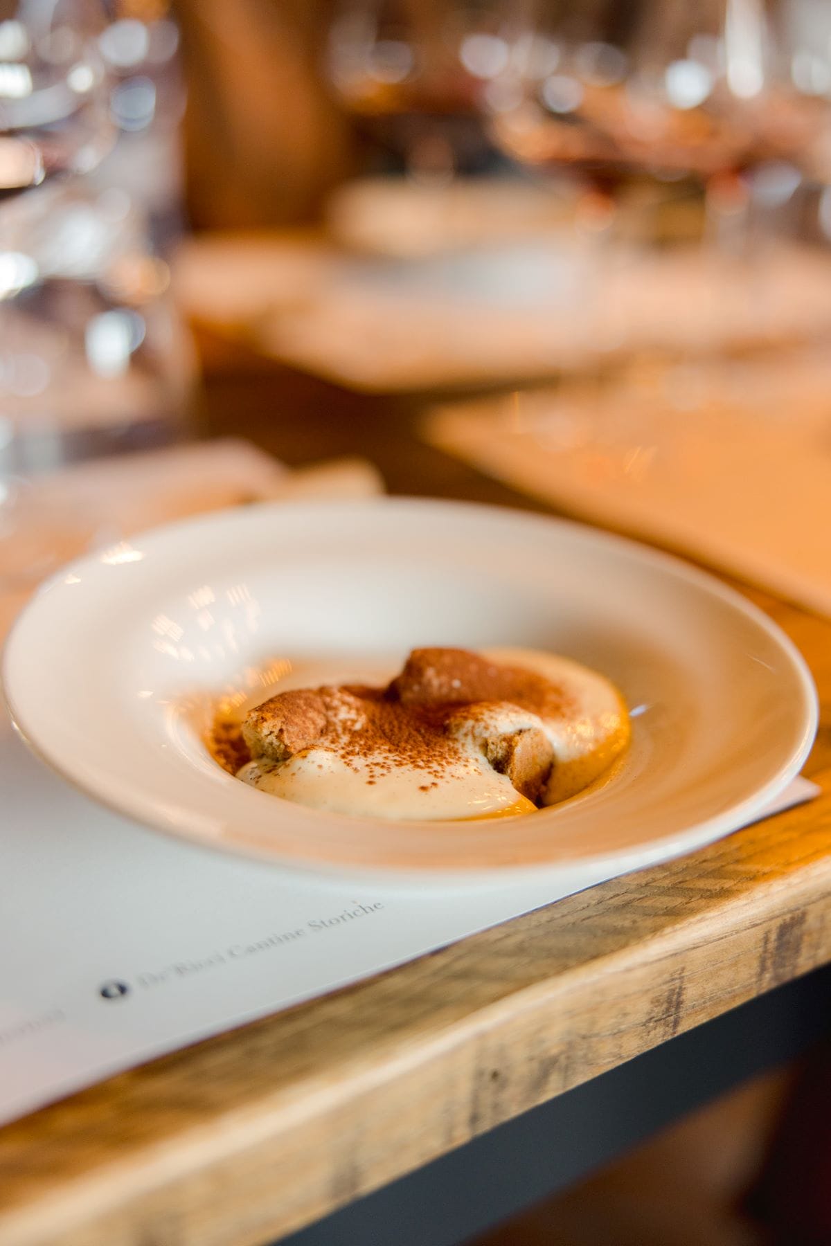 A plate of freshly made tiramisu in a white ceramic bowl.