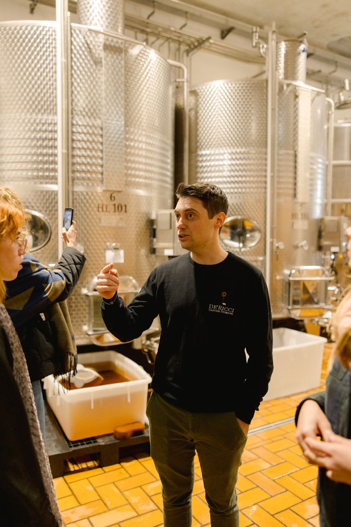 A wine owner explaining the wine making process to a group of people.