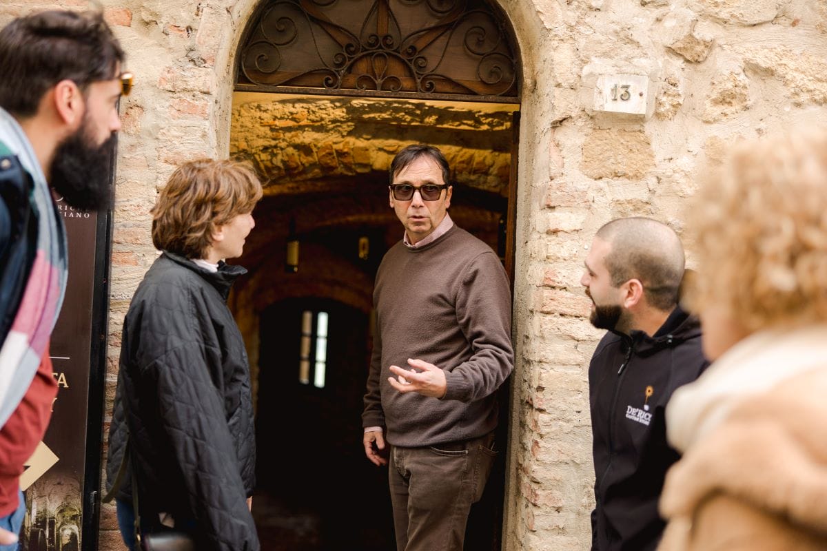 A group of people outside of a wine cellar about to enter.