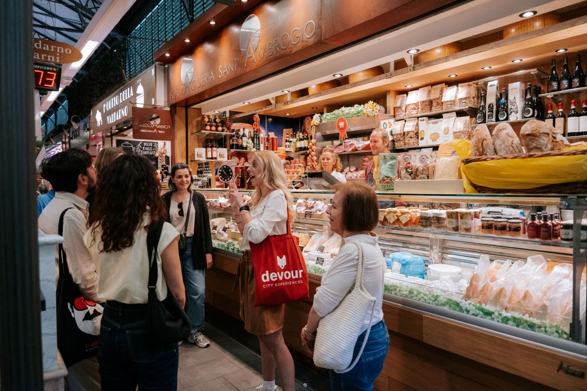 a group of people standing around a large food stall in a market