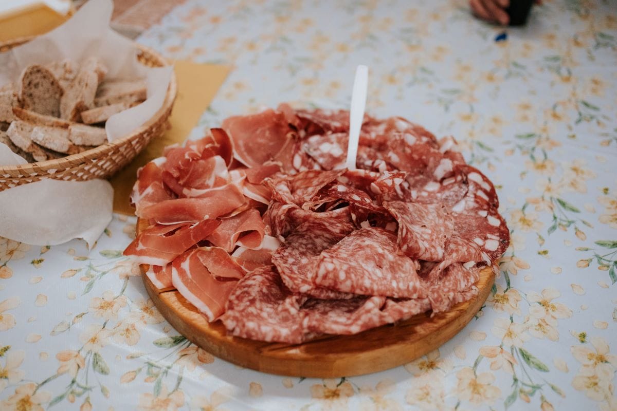 a round cutting board with slices of ham and salami