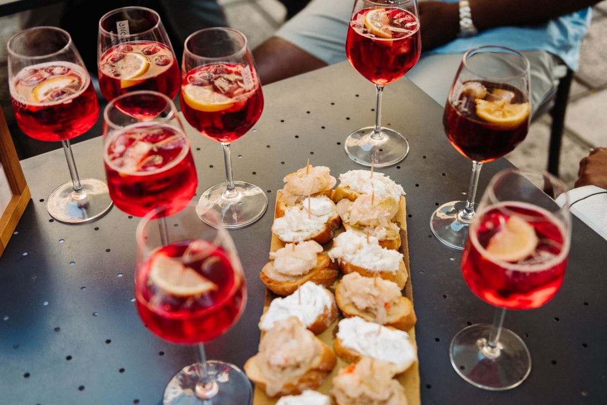 a table with various wine glasses and a plate of small toasts