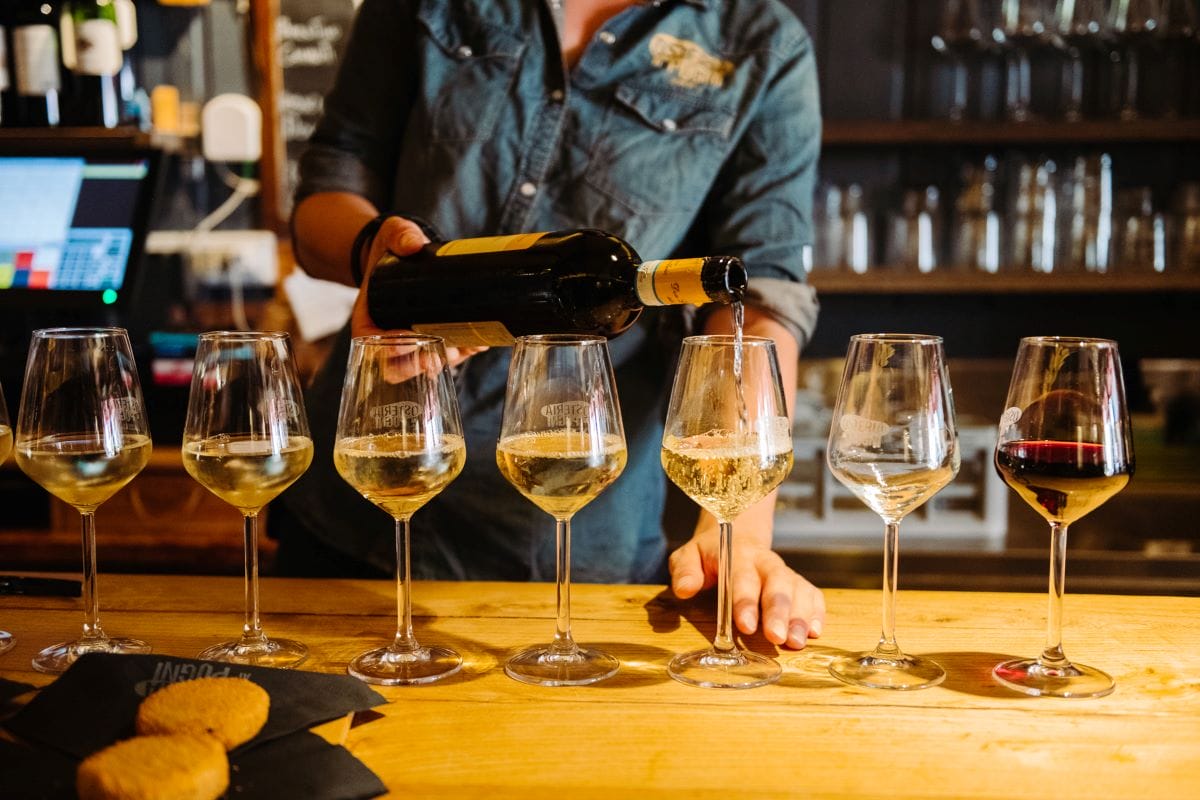 a woman pouring wine in several glasses of wine