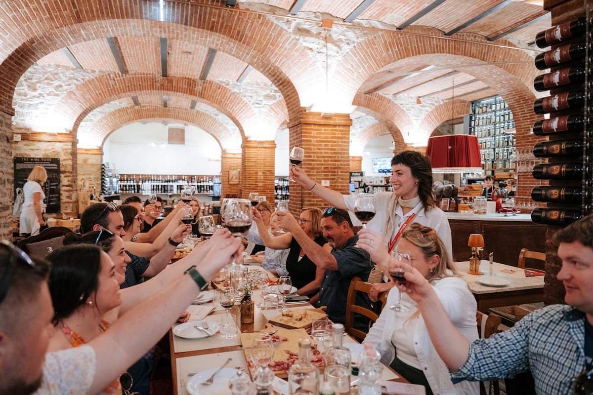 Group of people toasting with red wine in a vaulted restaurant