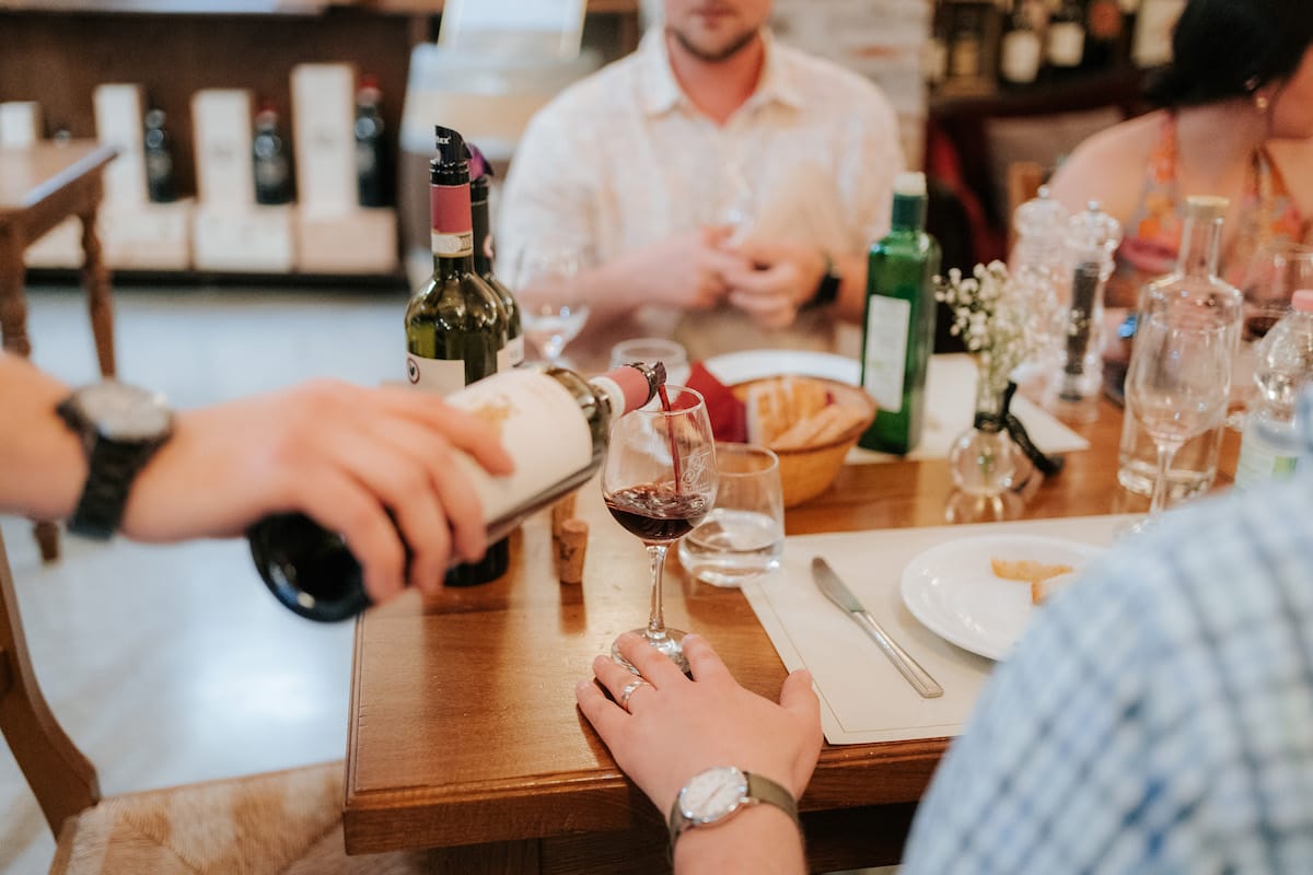 Person pouring a glass of red wine from the bottle, Chianti