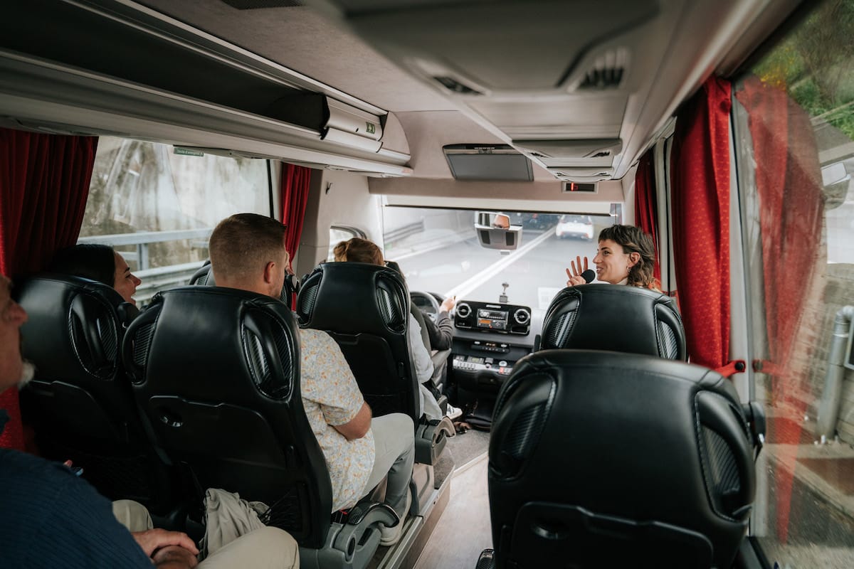 People listening to a tour guide speaking in a bus