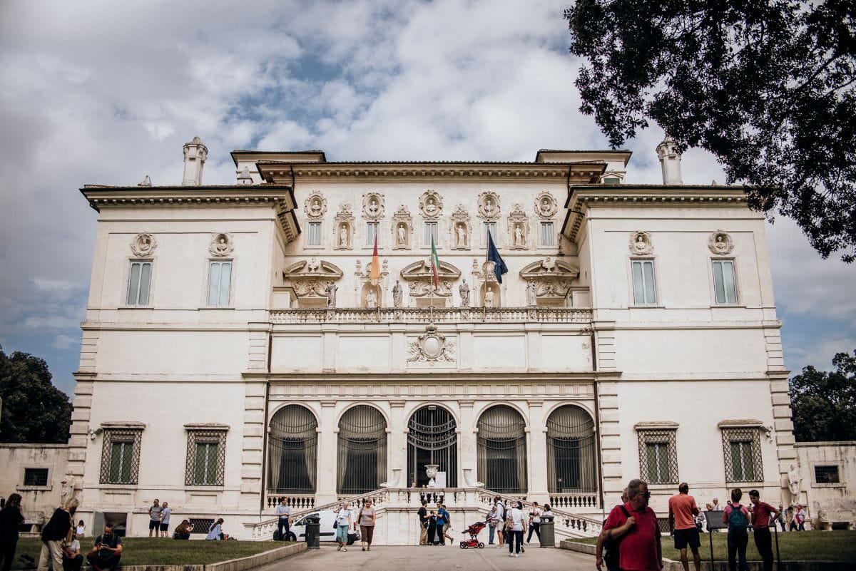 people standing outside large white building