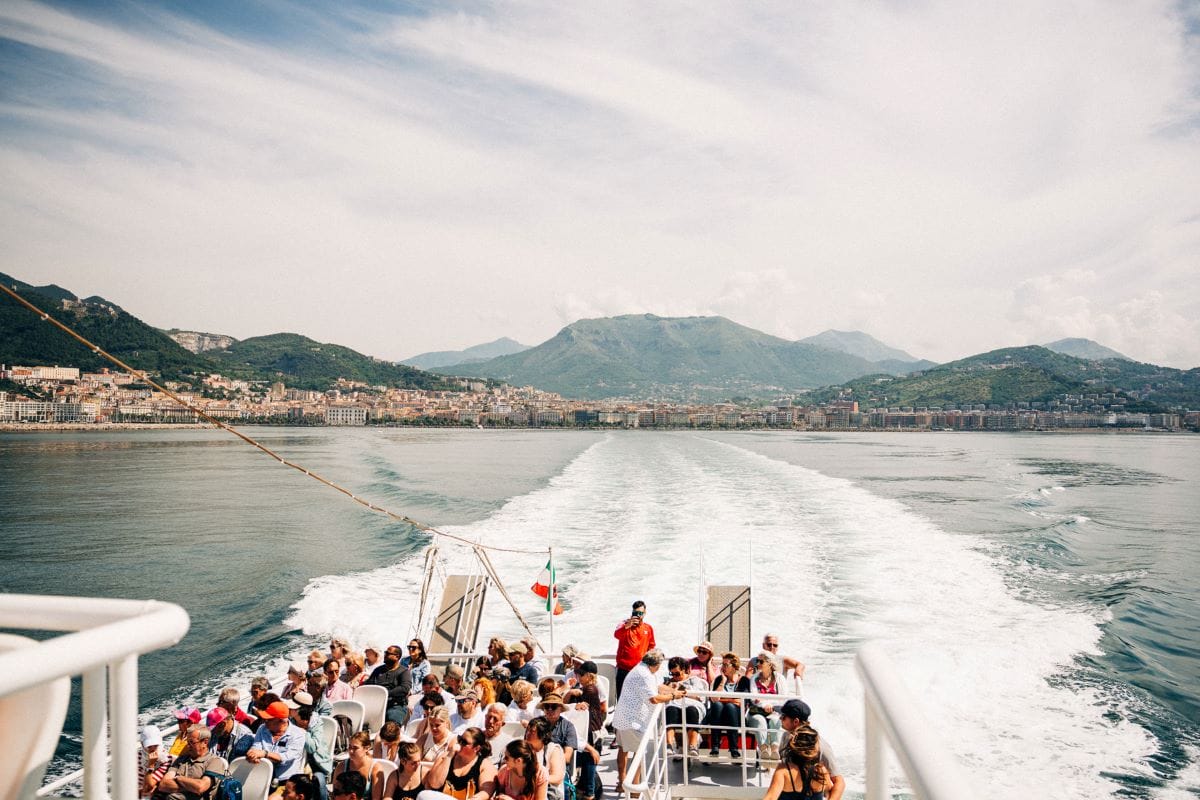 people on a boat with mountains and houses in the background