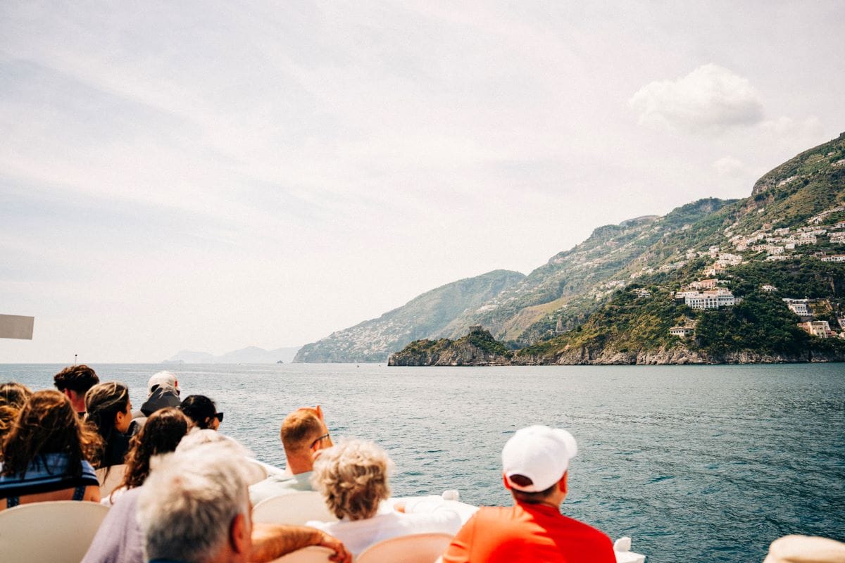 people looking at a beautiful view of colorful houses built on a cliffside overlooking the sea