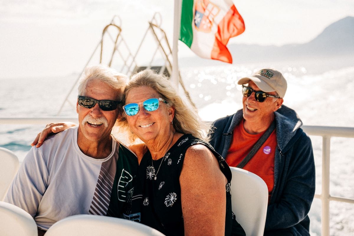 three people smiling on a boat ride